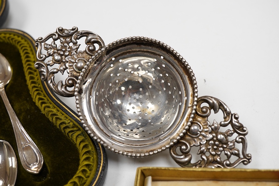 A cased set of six George V silver teaspoons and pair of sugar tongs, by Walker & Hall, Sheffield, 1918, together with a set of ten sterling coffee spoons, with floral terminals, a sterling tea strainer and a boxed Eliza